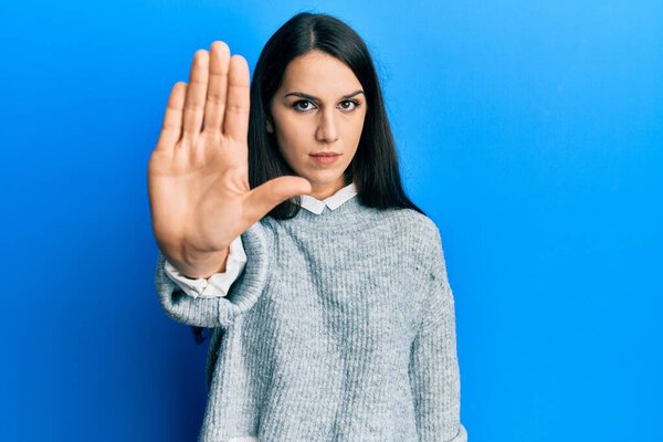 Young hispanic woman wearing casual clothes doing stop sing with palm of the hand. warning expression with negative and serious gesture on the face. 