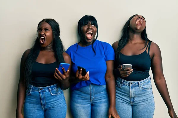 Troje Młodych Afrykańskich Przyjaciół Używających Smartfona Wściekłych Szalonych Krzyczących Sfrustrowanych — Zdjęcie stockowe
