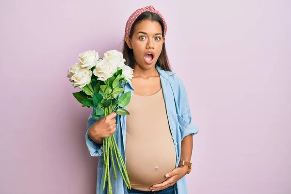 Mulher Hispânica Bonita Esperando Bebê Segurando Flores Com Medo Chocado — Fotografia de Stock