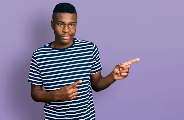 年轻的非洲裔美国人 手指指向侧面 脸上带着严肃的表情放松 简单而自然地看着相机 — 图库照片