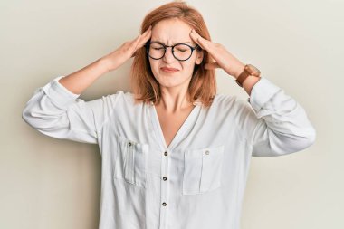 Kafası karışık, günlük kıyafetler ve gözlük takan genç beyaz bir kadın. Stres yüzünden baş ağrısı çekiyor. migren ağrısı. 