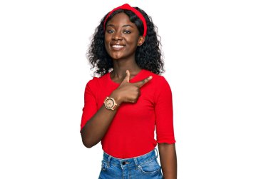 Güzel Afrikalı genç bir kadın. Neşeli ve neşeli giyinmiş. Yüzünde bir gülümseme var. 