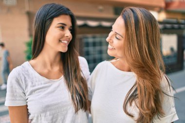 Güzel İspanyol anne ve kızı gülümseyerek şehirde mutlu mesut duruyorlar..