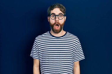 Sakallı, çizgili tişörtlü, gözlüklü, korkmuş ve şok olmuş beyaz bir adam.. 