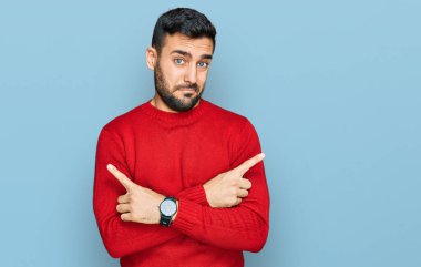 Gündelik kıyafetler giyen genç İspanyol adam her iki tarafı da parmaklarıyla işaret ediyor, farklı yönlerde farklı görüşler. 