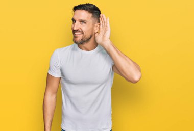 Sakallı, sıradan beyaz tişörtlü, ağzı kulaklarında, dedikoduları ve dedikoduları dinleyen yakışıklı bir adam. Sağırlık kavramı. 