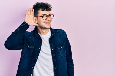 Gündelik giysiler ve gözlük takan genç İspanyol bir adam kulağından girip kulağına fısıldayarak dedikodu ve dedikoduları dinliyor. Sağırlık kavramı. 