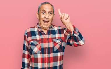 Gündelik kıyafetler giyen kıdemli İspanyol adam başarılı bir fikirle işaret ediyor. Heyecanlı ve mutlu. Bir numara.. 