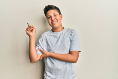 Gündelik gri tişörtlü, yüzünde kocaman bir gülümseme olan, eli ve parmağı kameraya bakan genç İspanyol çocuk.. 