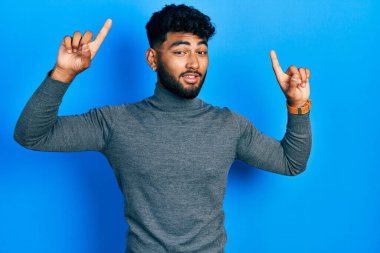 Balıkçı yaka kazak giyen, sakallı Arap adam şaşırmış, şaşırmış ve parmaklarını kaldırıp kollarını kaldırmıştı.. 