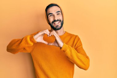 Gündelik kıyafetler giyen, aşık gülümseyen, elleriyle kalp sembolü yapan genç bir İspanyol. romantik kavram. 