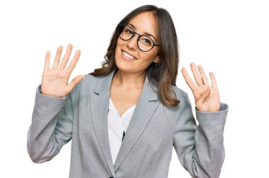 İş kıyafetleri giymiş genç esmer kadın dokuz numarayı gösterip işaret ederken kendinden emin ve mutlu bir şekilde gülümsüyor.. 