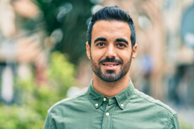 Genç İspanyol adam gülümseyerek şehirde mutlu mesut dikiliyor..