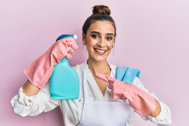 Önlük giymiş güzel esmer bir kadın temizlik spreyi tutuyordu. Gülümsüyordu. Elle ve parmakla işaret ediyordu. 