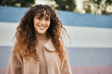 Genç İspanyol kadın gülümseyerek şehirde mutlu mesut dikiliyor.