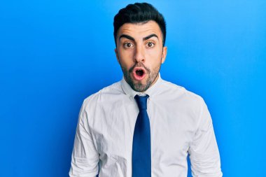 İş kıyafetleri giymiş genç İspanyol bir adam. Şaşırmış ve korkmuş bir ifade, korku ve heyecanlı bir yüz ifadesi var.. 