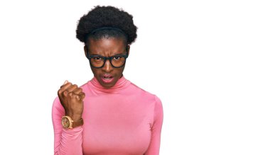 Genç Afro-Amerikalı kız günlük kıyafetler ve gözlük takıyor kızgın ve kızgın yumruk kaldırıyor öfkeyle bağırırken sinirli ve öfkeli. öfke ve agresif konsept. 