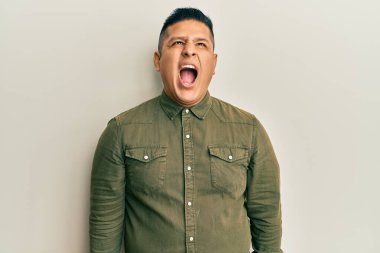 Gündelik kıyafetler giyen genç latin adam kızgın ve kızgın bağırıyor sinirli ve öfkeli, öfkeyle bağırıyor. öfke ve agresif konsept. 