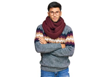 Kış süveteri giyen genç yakışıklı adam kuşkucu ve gergin. Yüzünde çapraz kollu tasvip etmeyen bir ifade var. negatif kişi. 