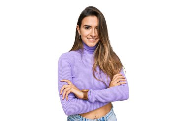 Gündelik kıyafetler giyen, kollarını kavuşturup kameraya gülümseyen genç İspanyol kadın. pozitif kişi. 