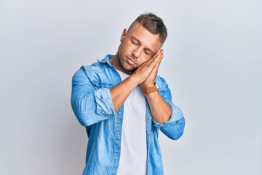 Yakışıklı kaslı adam rahat bir kot ceket giyer, uyur, yorgun düşler kurar, elleriyle poz verir, gözleri kapalı gülümserdi.. 