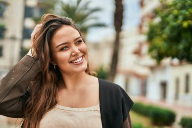 Genç İspanyol kadın gülümseyerek şehirde mutlu mesut dikiliyor..