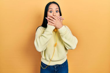 Boynuna kulaklık takmış, burun piercingli güzel bir İspanyol kadın ağzını yanlışlıkla ellerle kapatmış. gizli kavram. 