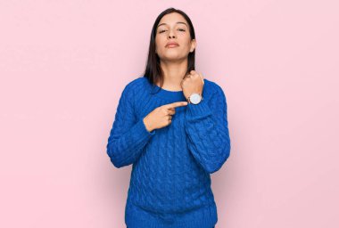 Gündelik kıyafetler giyen genç İspanyol kadın saati, sabırsızlığı ve rahat bir ifadeyle kameraya bakmayı işaret ediyor. 