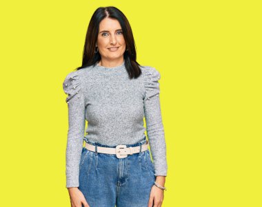 Orta yaşlı esmer kadın mutlu ve havalı bir gülüşü olan sıradan kıyafetler giyiyor. şanslı kişi. 