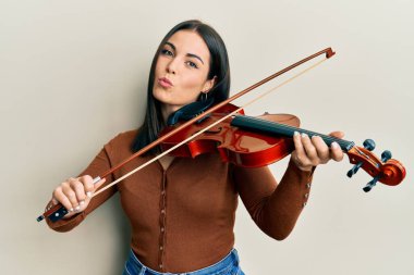 Genç esmer kadın keman çalıyor kameraya bakıyor ve öpüşüyor. Güzel ve seksi. aşk ifadesi. 