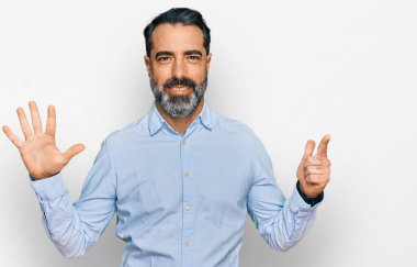 Orta yaşlı, sakallı, iş gömleği giyen, 7 numaralı parmaklarıyla işaret eden, kendine güvenen ve mutlu bir adam.. 