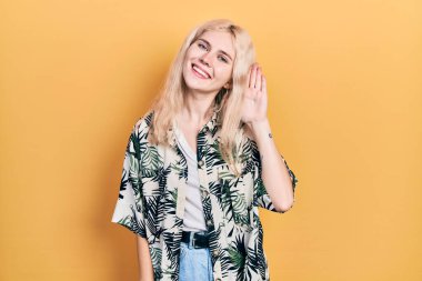 Sarışın, tropikal tişörtlü, güzel beyaz bir kadın. Kulağı kulağında gülümseyen, dedikoduları ve dedikoduları dinleyen. Sağırlık kavramı. 