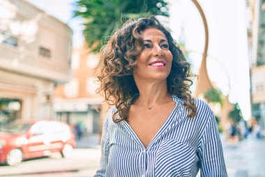 Orta yaşlı İspanyol kadın gülümseyerek şehirde mutlu mesut yürüyor..