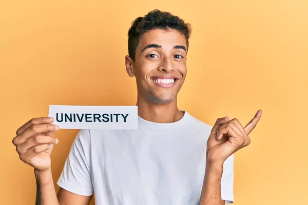 Joven Hombre Afroamericano Guapo Sosteniendo Papel Con Palabra Universitaria Sonriendo — Foto de Stock