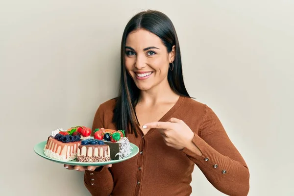 Junge Brünette Frau Hält Teller Mit Kuchenscheiben Und Lächelt Glücklich — Stockfoto