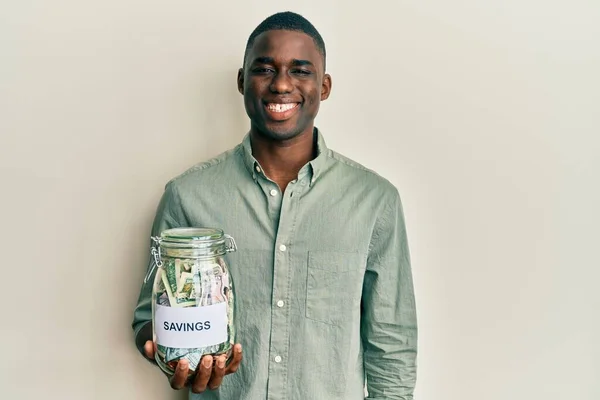 年轻的非洲裔美国人拿着装有储蓄的罐子 面带微笑 面带微笑 面带微笑 看上去很积极 很快乐 — 图库照片
