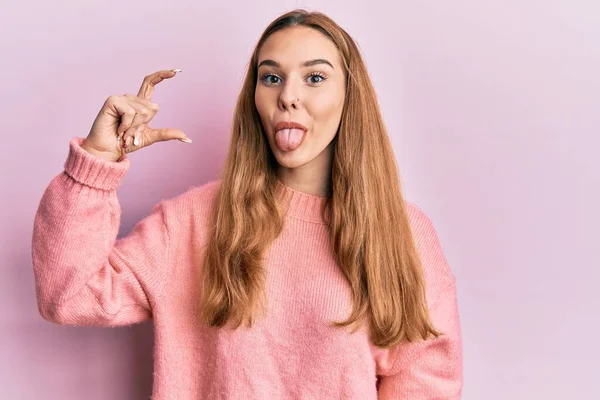 Young Blonde Woman Doing Measure Gesture Fingers Sticking Tongue Out — Stock Photo, Image