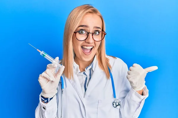 Beautiful Caucasian Woman Wearing Doctor Stethoscope Holding Syringe Pointing Thumb — Stock Photo, Image