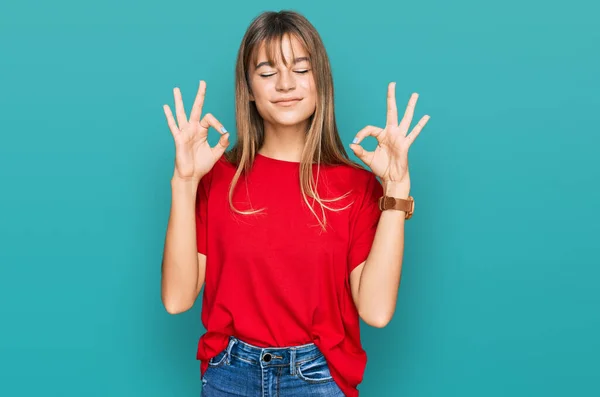 十几岁的白人女孩穿着宽松的红色T恤 闭着眼睛微笑 用手指做冥想动作 瑜伽概念 — 图库照片