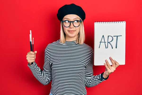 Hermosa Mujer Rubia Sosteniendo Cuaderno Arte Cepillos Sonriendo Mirando Hacia — Foto de Stock