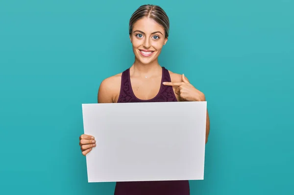 Beautiful Blonde Woman Wearing Sportswear Holding White Banner Pointing Finger — Stock Photo, Image