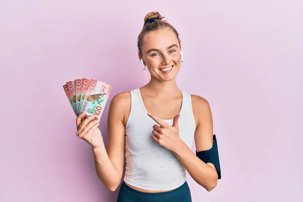 Beautiful Blonde Sport Woman Holding 100 New Zealand Dollars Banknote — Stock Photo, Image