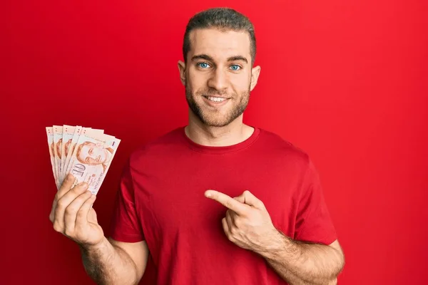 Joven Hombre Caucásico Sosteniendo Billetes Dólares Singapur Sonriendo Feliz Señalando —  Fotos de Stock