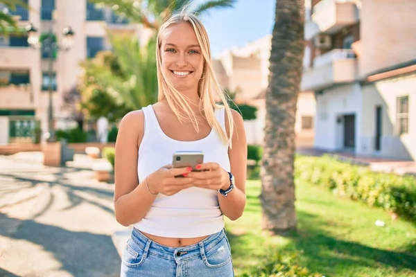 若いですブロンド女の子笑顔幸せな使用スマートフォンでザ公園 — ストック写真