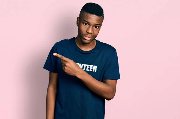 Hombre Afroamericano Joven Con Camiseta Voluntaria Señalando Lado Preocupado Nervioso —  Fotos de Stock