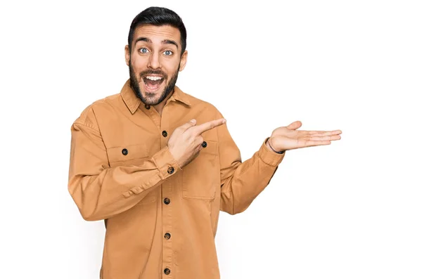 Jovem Hispânico Vestindo Roupas Casuais Espantado Sorrindo Para Câmera Apresentar — Fotografia de Stock