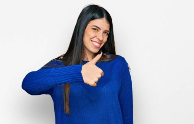 Gündelik kıyafetler giyen genç İspanyol kadın elleriyle mutlu bir jest yapıyor. Kameraya bakıp başarıyı gösteren ifade. 