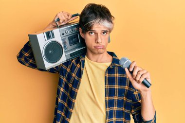 Genç İspanyol adam mikrofon ve teyp kullanarak şarkı söylüyor. Depresyonda ve endişe içinde, sinirli ve korkmuş bir şekilde. hüzünlü ifade. 