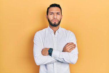 Sakallı, iş gömleği giyen, kuşkucu ve gergin İspanyol bir adam. Yüzünde çapraz kollu, onaylamayan bir ifade var. negatif kişi. 