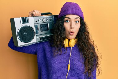 Kıvırcık saçlı genç esmer kadın, müzik dinliyor, korkmuş ve şaşırmış bir şekilde ağzı açık, inançsız bir yüz. 